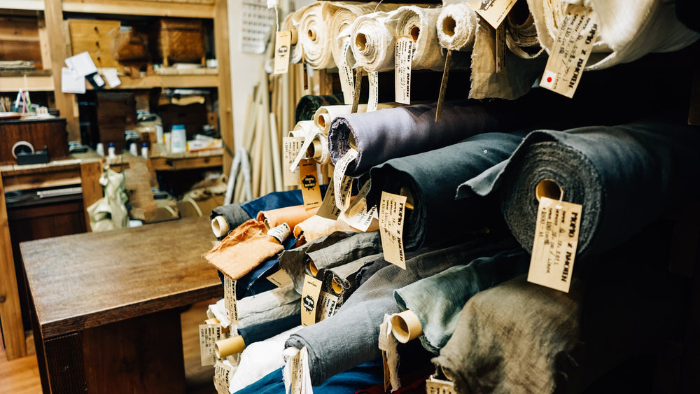 Rolls of assorted fabrics on wooden shelves in a fabric store, showcasing various colors and textures for sewing and quilting projects.
